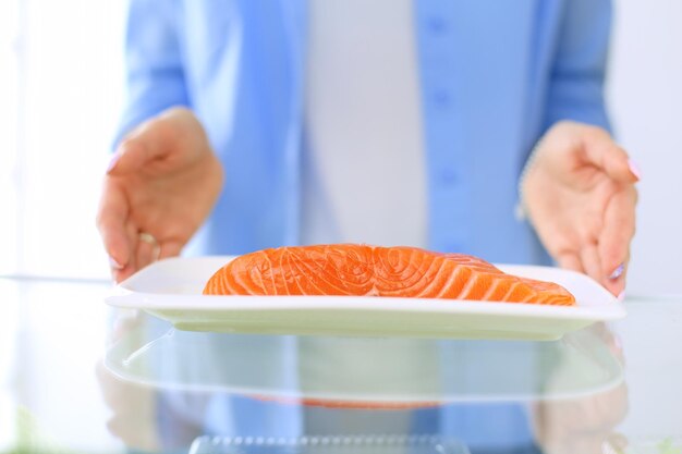 健康食品の野菜や果物でいっぱいの開いた冷蔵庫の近くに立っている女性の肖像画