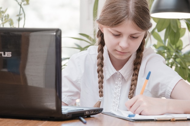 Portrait of female student enjoying learning in coworking office using laptop computer for research, freelancer during making project for remote job making notes. Pupil concentrated drawing notes