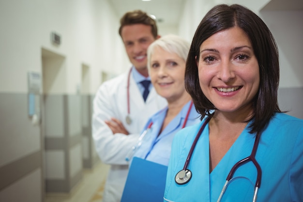 Portrait of female surgeon and doctors standing in corridor