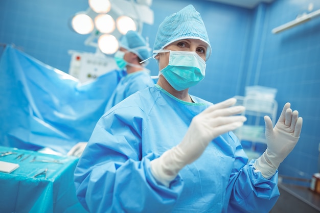 Портрет женского хирурга, стоя в операционном зале