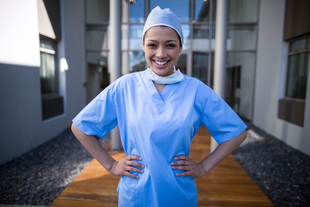 Portrait of female surgeon standing with hands on hip