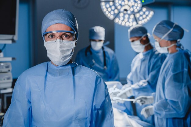 Portrait of female surgeon wearing scrubs and protective
glasses in hospital operating theater