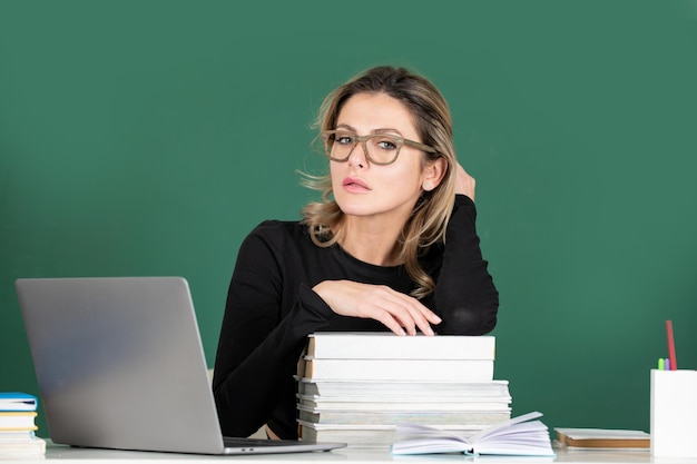 Portrait of female teacher teaching line of high school\
students with computer laptop in classroom