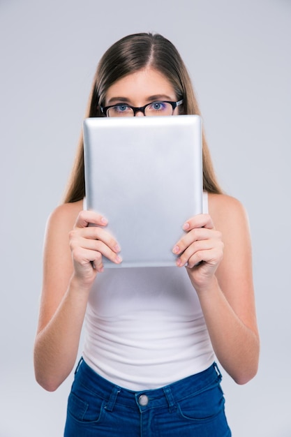 Portrait of a female teenager covering her face with tablet computer isolated