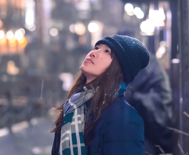 Portrait of Female tourist traveling in Ginzan Onsen with snow falling at night