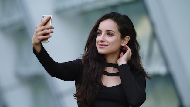 路上でビデオ通話を使用する肖像画の女性 スマートフォンを使用してセクシーな実業家