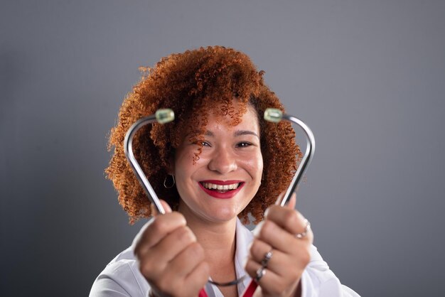 Foto ritratto di una veterinaria donna con i capelli rossi che indossa un'uniforme bianca e tiene uno stetoscopio vicino al viso cura degli animali isolato su sfondo grigio