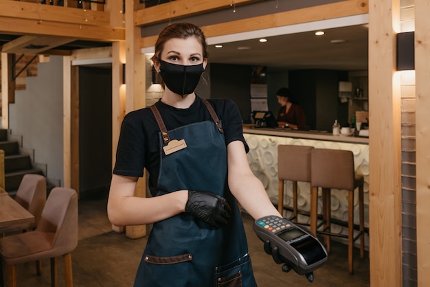 portrait female waitress holding a wireless payment terminal