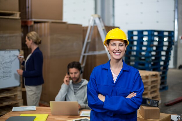 Portrait of female warehouse worker standing with arms crossed