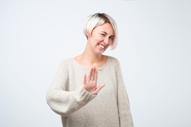 Photo portrait of female with dyed hairstyle shows refusal or stop sign tries to prevent herself from something unpleasant