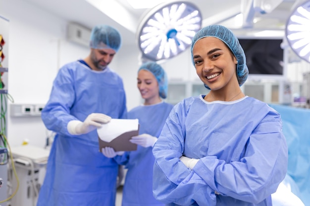 Portrait of female woman nurse surgeon OR staff member dressed in surgical scrubs gown mask and hair net in hospital operating room theater making eye contact smiling pleased happy looking at camera