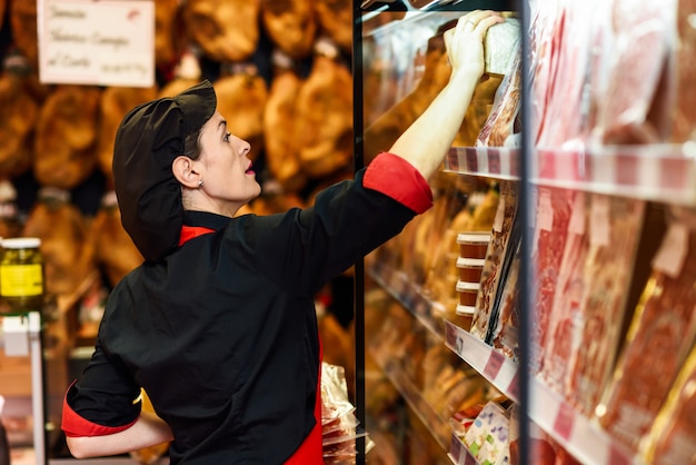 Portrait of female worker taking products in butcher shop