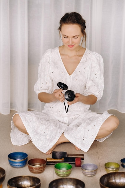 Photo portrait of a female yoga teacher playing a tibetan bowl or singing a bell in the gym during a yoga retreat