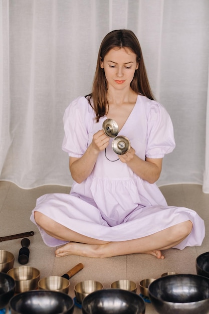 Portrait of a female yoga teacher playing a Tibetan bowl or singing a bell in the gym during a yoga retreat