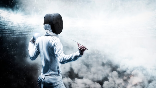 Portrait of a fencer against the backdrop of a sports arena. Smoke and sparks, mystical background. The concept of fencing. Back view. Mixed media