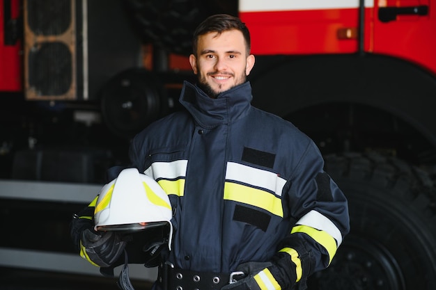 Portrait of a firefighter standing in front of a fire engine