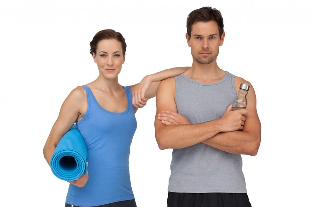 Portrait of a fit couple with exercise mat and water bottle