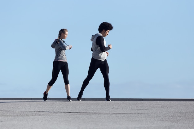 Portrait of fit and sporty couple running in the street.