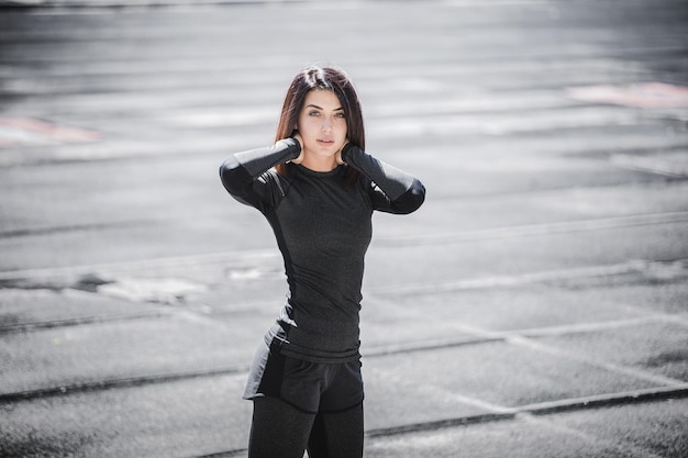 Portrait of fit and sporty young woman doing stretching in city