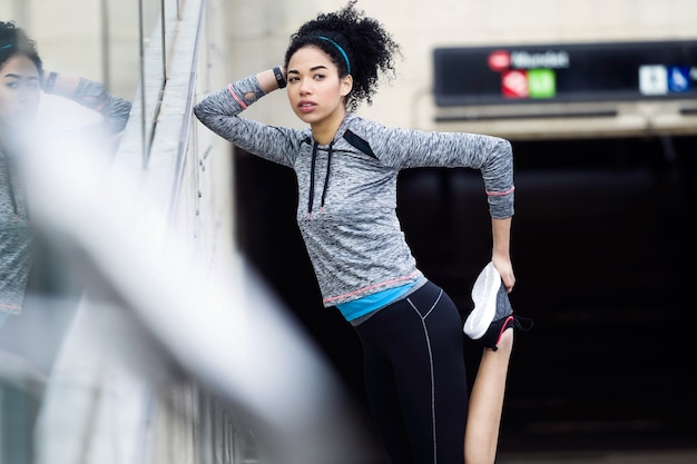 Portrait of fit and sporty young woman doing stretching in city.