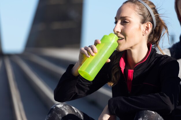 Photo portrait of fit and sporty young woman drinking water.