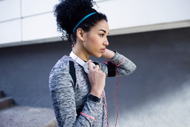 Ritratto di giovane donna sportiva e in forma che ascolta musica con il telefono cellulare.