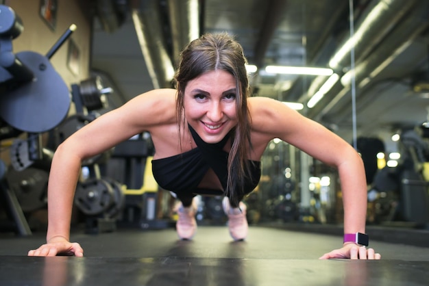 Portrait of fit strong muscle young happy woman in a good shape training in a gym fitness centre