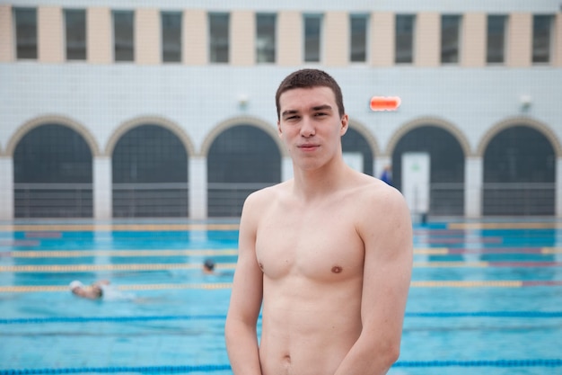 Портрет здорового пловца в бассейне, смотрящего в камеру Портрет конкурентоспособного пловца возле бассейна