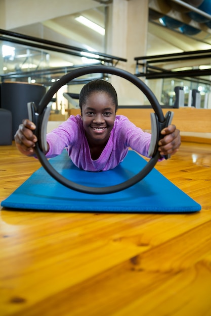 Ritratto di donna adatta che si esercita con anello di pilates in studio fitness