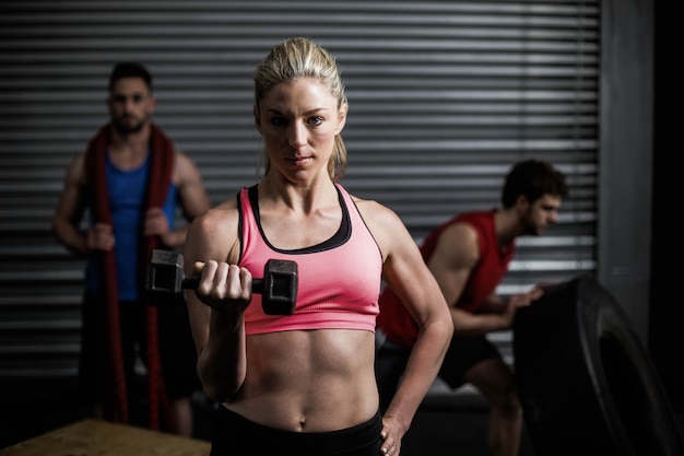 Portrait of fit woman lifting dumbbells at crossfit gym