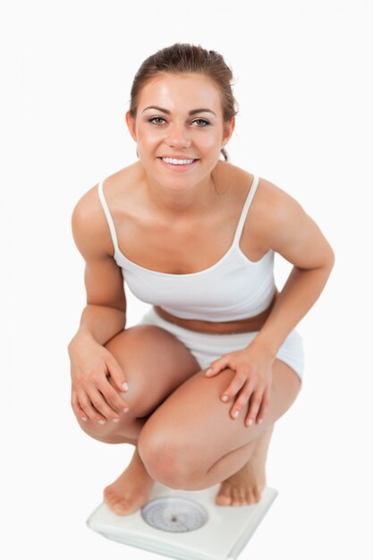 Portrait of a fit woman squatting on scales