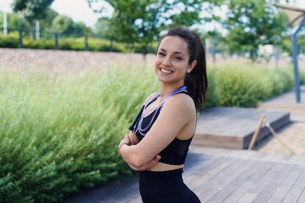 Portrait of fit young woman with jump rope in a park fitness female doing skipping workout outdoors