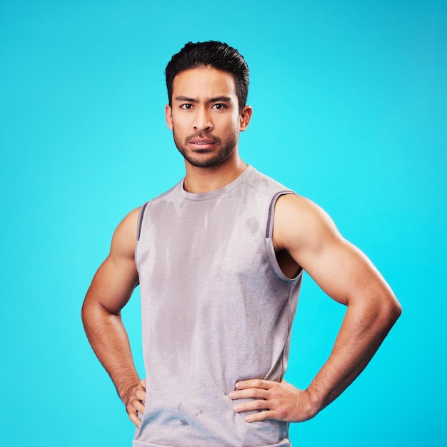 Portrait fitness and confident Asian man sweat in studio isolated on a blue background Face serious and personal trainer with exercise workout or sports for healthy body or wellness in Cambodia