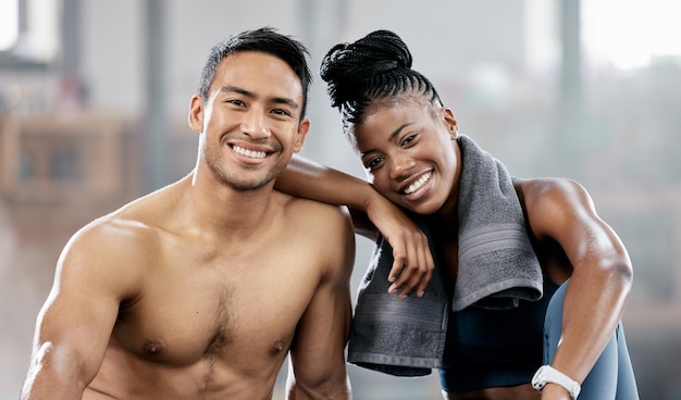 Portrait fitness and diversity with a sports couple sitting in the gym together after a workout for health Exercise happy and strong with a man and woman athlete sitting in a training facility