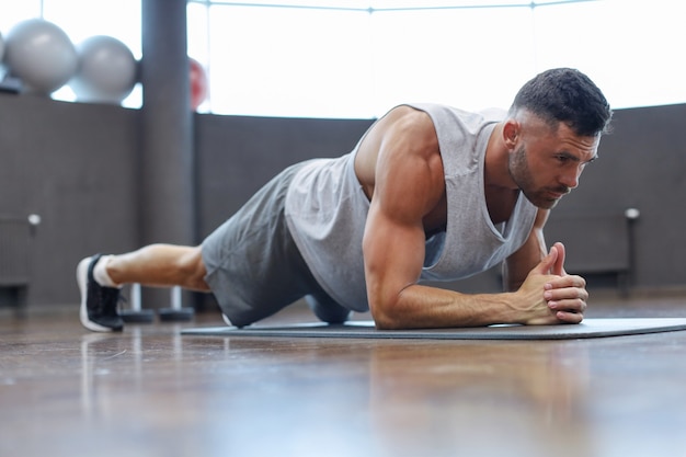 Portrait of a fitness man doing planking exercise in gym.