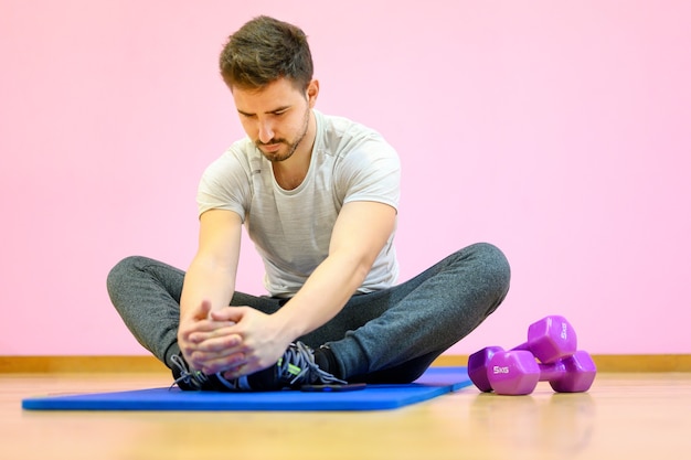 Portrait of a fitness man doing stretching exercises at gym