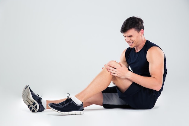 Photo portrait of a fitness man suffering from pain in a knee isolated