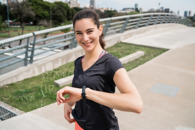 Portrait of a fitness woman checking time on her smart watch. Sport and healthy lifestyle concept.