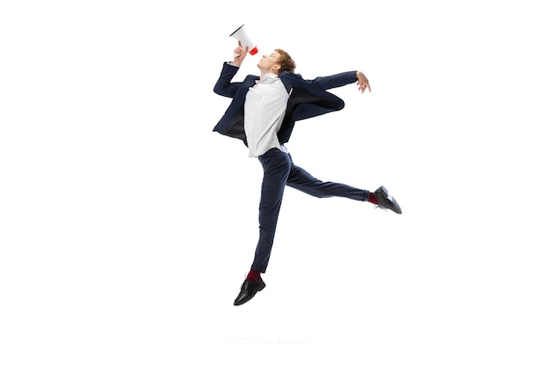 Portrait of flexible man in business style clothes jumping with megaphone isolated on white studio background