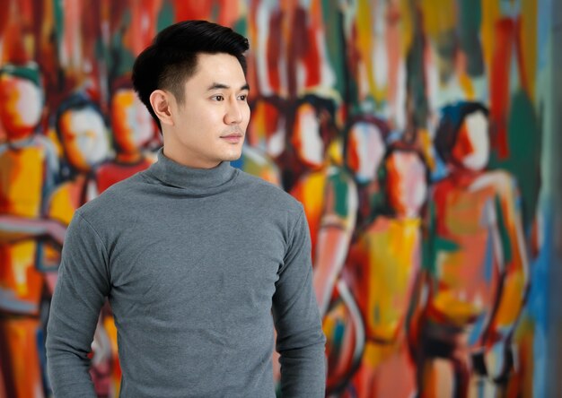 Photo portrait fo asian man handsome smiling looking away wearing gray long sleeve t-shirt standing on a artistic picture background.