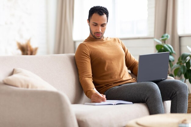 Portrait of focused arab man using laptop and writing