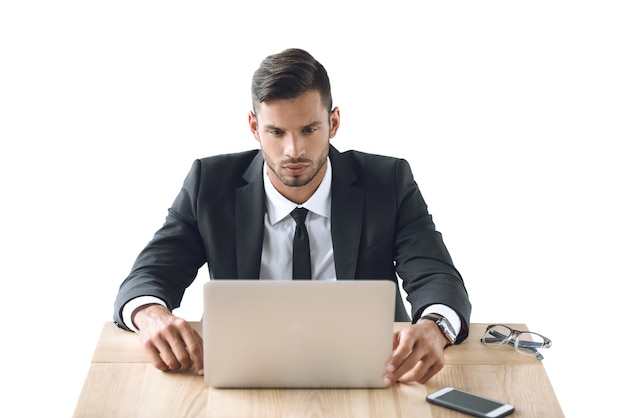 Portrait of focused businessman working on laptop at workplace isolated on white