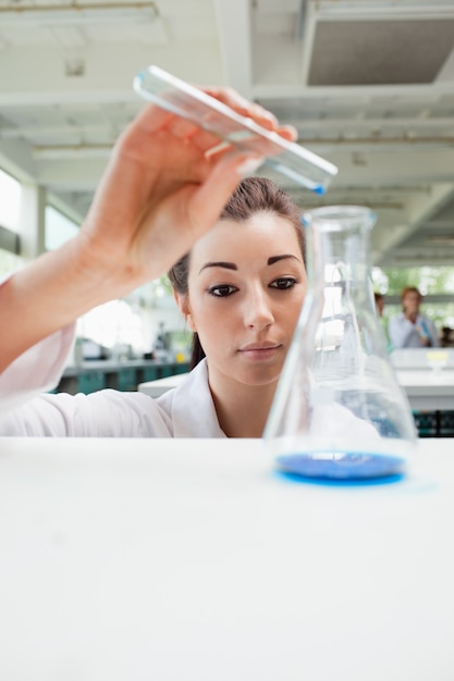 Foto ritratto di uno studente di scienze concentrato versando liquido