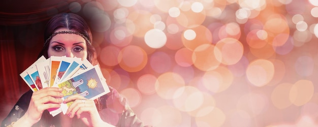 Портрет гадалки, скрывающей рот с картами Таро на светящемся фоне