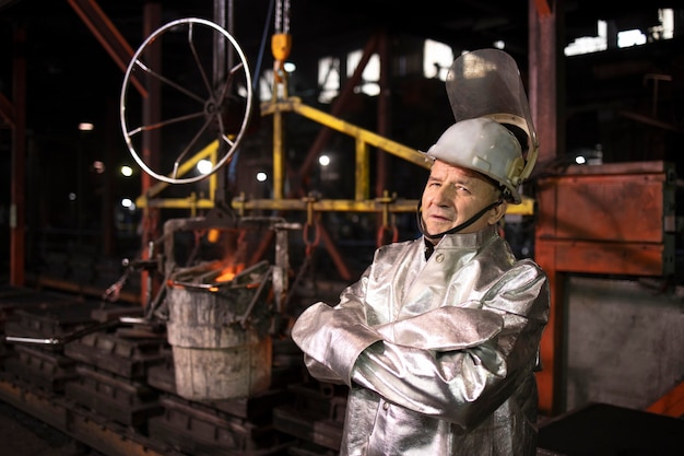 Portrait of foundry worker standing by hot molten steel in production plant.