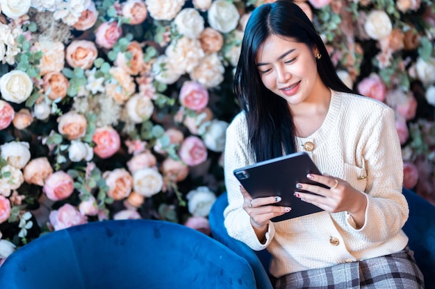 Portrait freelance business beautiful positive smile young asian woman online working with using tablet at home in the living room indoors or the cafeBusiness Lifestyle and rose background