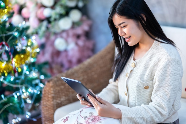 Portrait freelance business beautiful positive smile young asian woman online working with using tablet at home in the living room indoors or the cafeBusiness Lifestyle and rose background