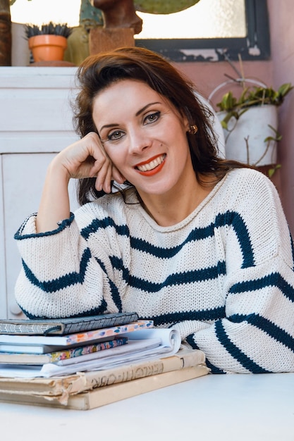 portrait french caucasian adult student woman sitting smiling and looking at camera leaning on table