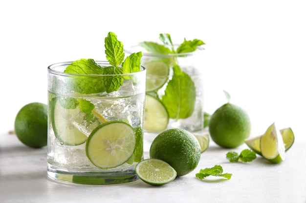 Portrait of fresh mojito cocktail with fresh limes, mint, and ice isolated on white