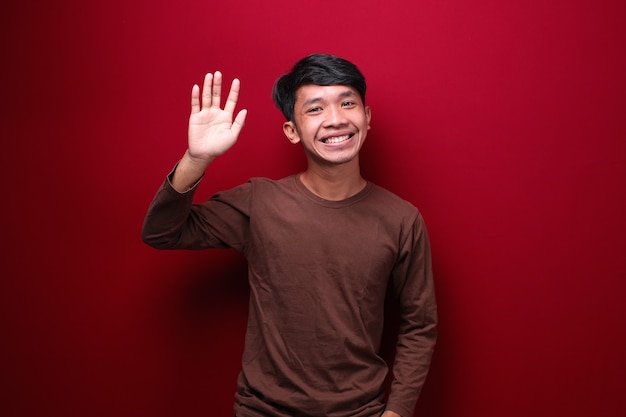 Portrait of friendly cheerful asian man saying hi welcome person as waving hand